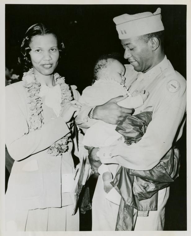 African American officer standing next to his wife and holding his baby son in his hands, Honolulu