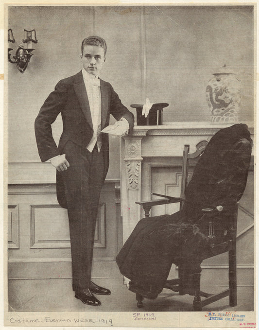 Man in tuxedo near a fireplace and chair, United States, ca. 1919