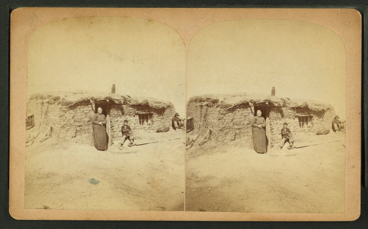 Three people in front of a sod house.