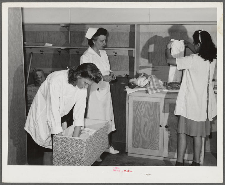 Eleven Mile Corner, AZ. FSA farm workers' community. Girls, who live at the NYA resident center learning baby care. The nurse, who divides her time between working at the hospital and instructing the NYA girls, is showing them how to care for a well baby