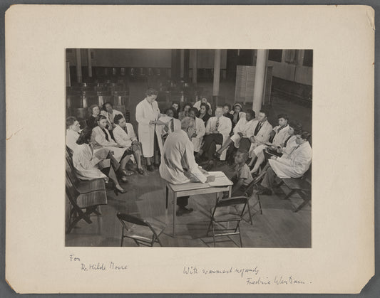 Group portrait of doctors in white coats including Hilde Mosse and Fredric Wertham examining a child