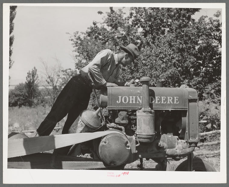 Farmer looking at the tank of tractor to see if it needs fuel. Box Elder County, Utah