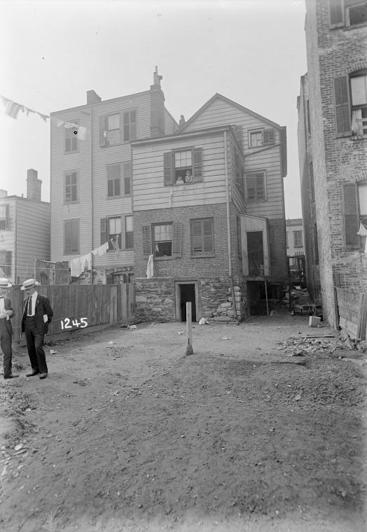 Tenement backyard with laundry & two men in suits