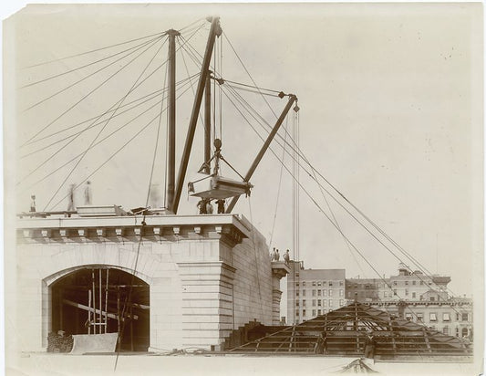 Exterior marble work : construction workers lowering a piece of marble into place on the roof, looking north
