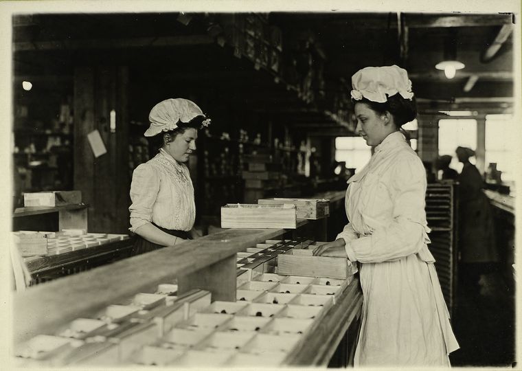 Two women sort chocolates, facing each other