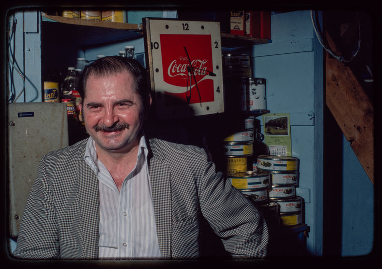 Man seated in front of Coca-Cola clock, Plaza de Athena I