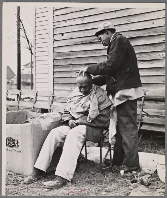 Negro getting a haircut in front of church which houses flood refugees. Sikeston, Missouri