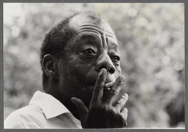 James Baldwin looking contemplative while smoking cigarette