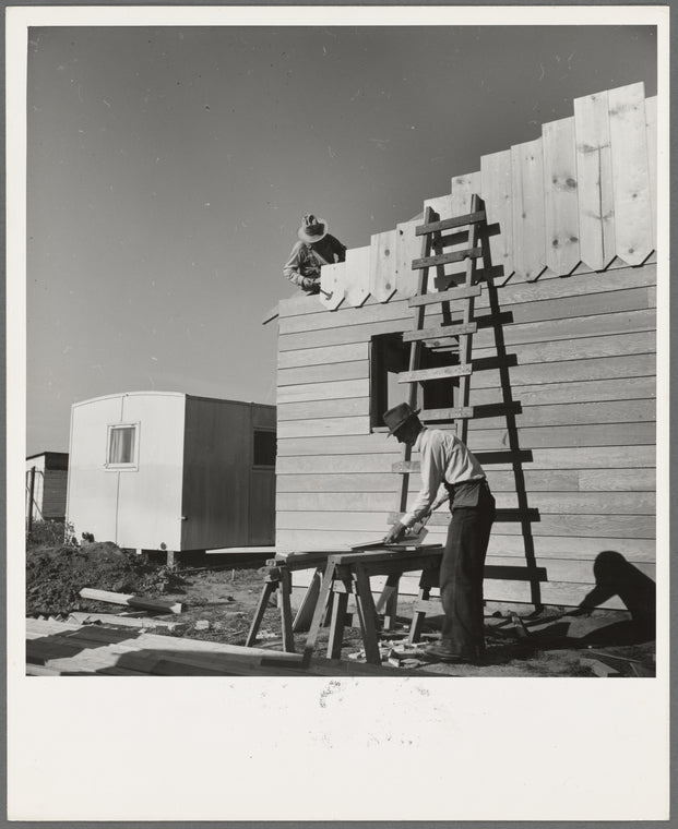 Father and son, recent migrants to California, building house in rapidly growing settlement of lettuce workers on fringe of town. Salinas, California