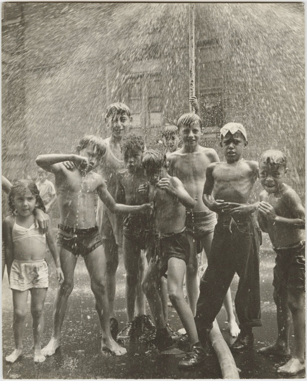 Group of children, mostly boys, gathered under sprinkler, in East Harlem, New York City
