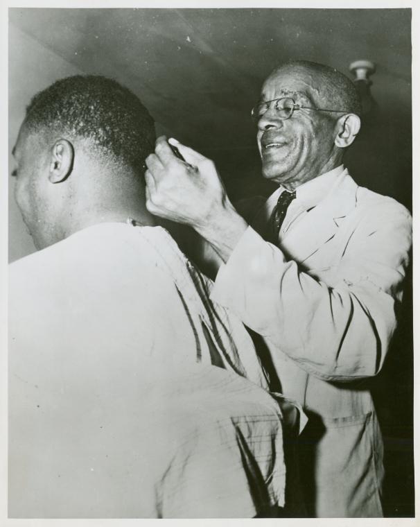 African American veteran Joseph N. Stevens, 72, cutting the hair of an African American serviceman, Fort Benning, Georgia
