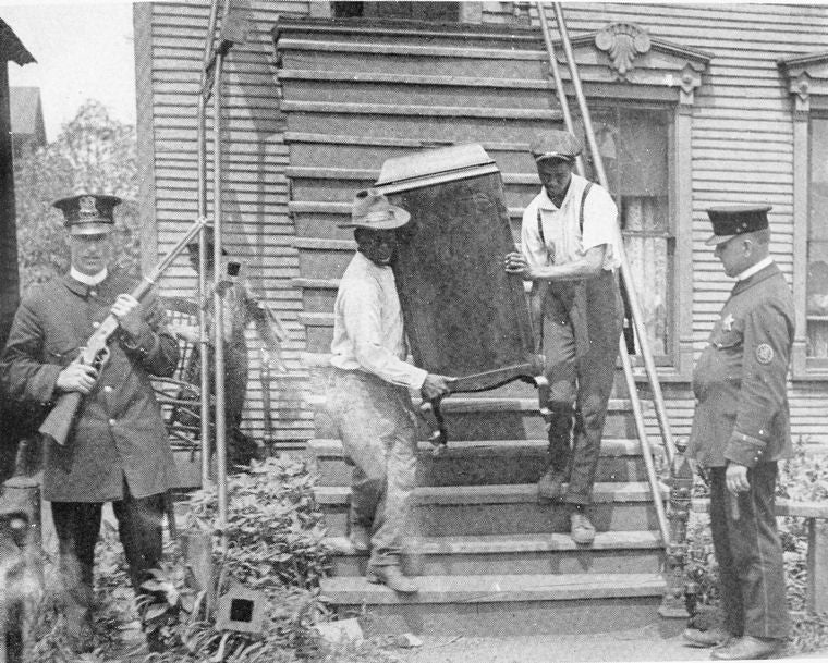 Negroes under protection of police leaving wrecked house in riot zone.