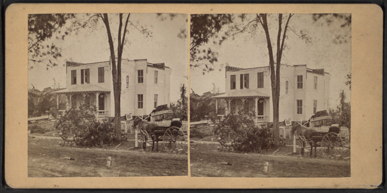 Debris littering the yard of a damaged house with fences.