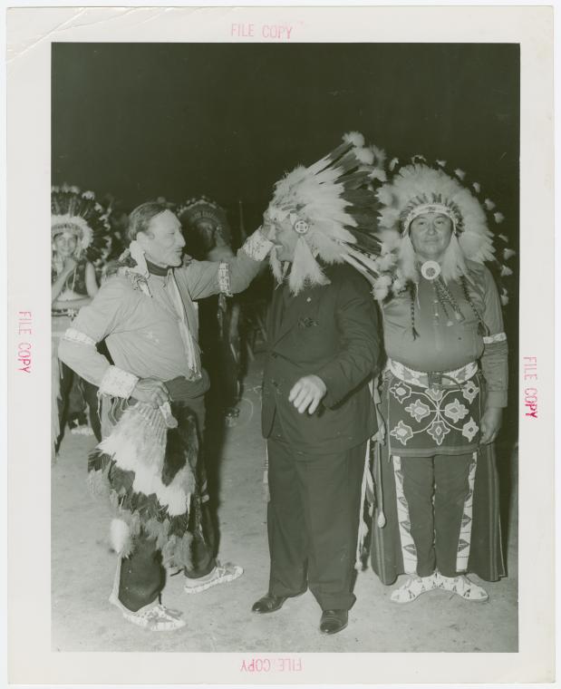 Amusements - Shows and Attractions - Wild West - Indian man putting headdress on Grover Whalen