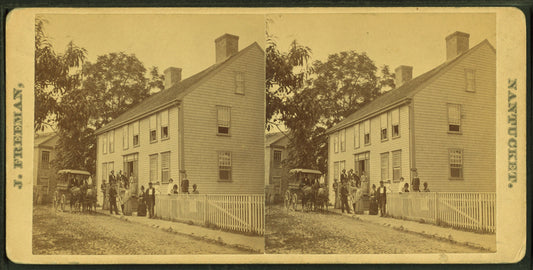 Group posing on porch of large house, possibly a boarding house, with wagonette standing by.