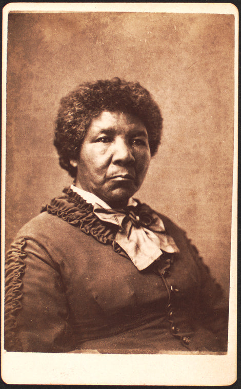 Studio portrait of unidentified woman dressed in a rouched jacket and large striped bow at neck.