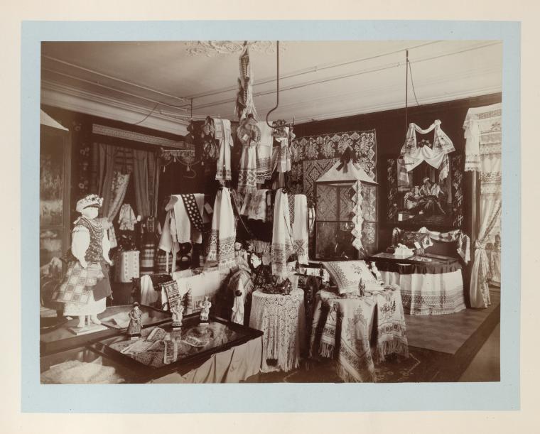 Large room with displays of embroidery towels, tableclothes, pillow cases, costumes, dolls and napkins, etc.