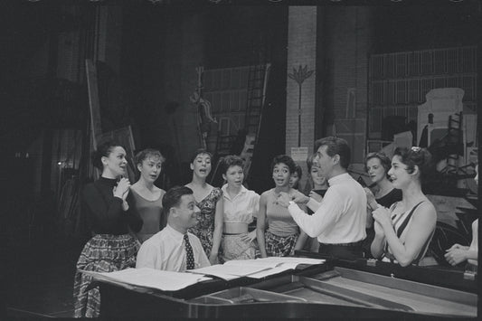 Chita Rivera, Stephen Sondheim, Leonard Bernstein, Carol Lawrence, and cast around piano in rehearsal for the stage production West Side Story