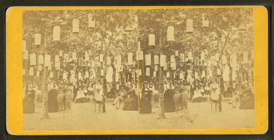People sitting and standing under chinese lanterns.