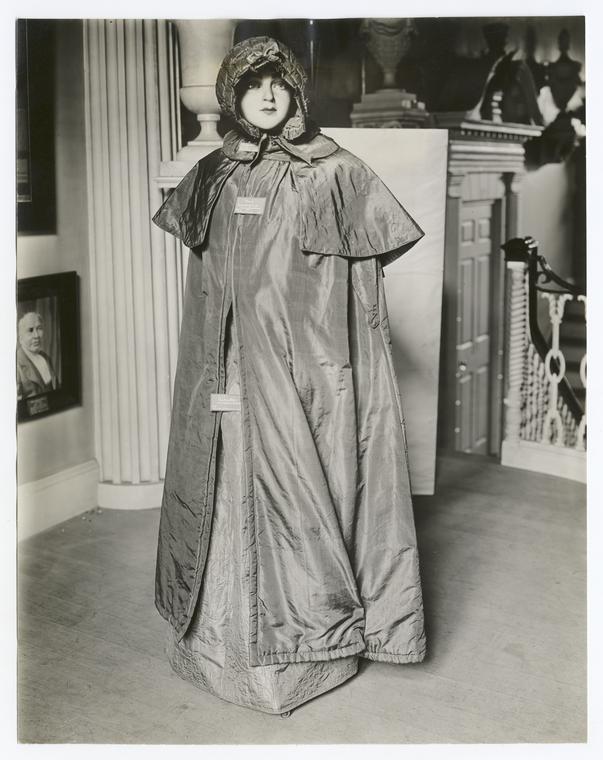 Costume, cloak, olive silk, worn by Mrs. Moses Adams, (Sarah Hubbard). Pumkin hood, quilted plum color silk, from Robbins family of Lexington, Mass.