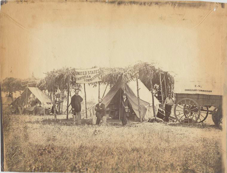 [Four men in front of sheltered tent next to U.S. Christian Commission wagon, another tent at rear left.] / Alexander Gardner