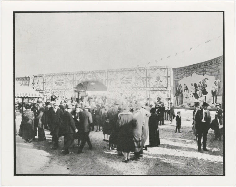 C.W. Parker Amusement Company operated carnival, ca. 1920s. Signage for burlesque shows, as well as groups of stage performers, are in the far background