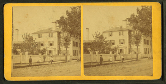 People in front of a large house with fence.
