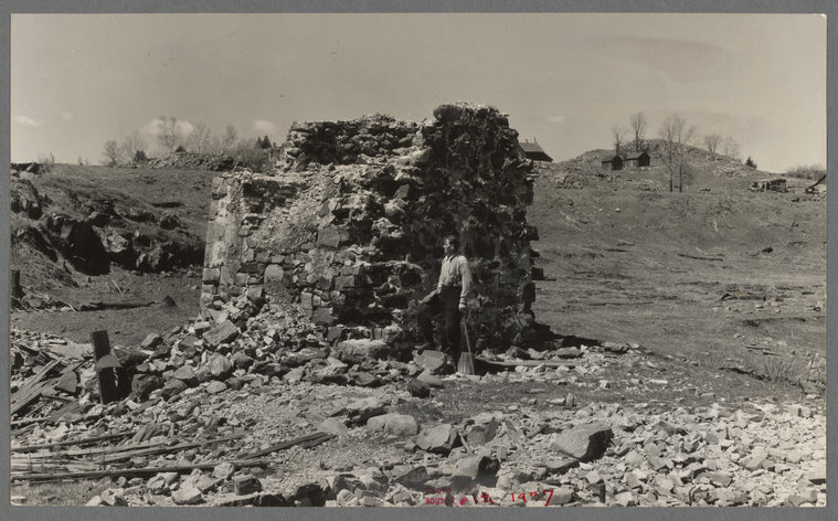Mr. Henrickson, one of the old timers at Mansfield, Michigan, standing at the base of the former one hundred foot smokestack of an abandoned iron mine. This is one of the few recognizable remains of the mine