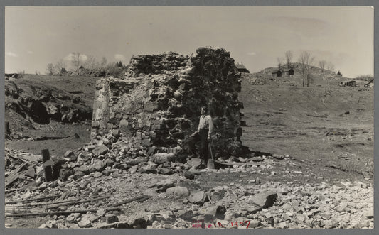 Mr. Henrickson, one of the old timers at Mansfield, Michigan, standing at the base of the former one hundred foot smokestack of an abandoned iron mine. This is one of the few recognizable remains of the mine