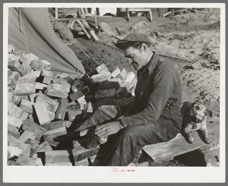 Man who is building a new trailer court scraping secondhand brick which will be used in building a cesspool. San Diego, California. New trailer courts are springing up monthly because they seem to be the preferred type of housing
