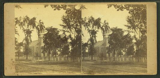 Church bordered with trees, road in foreground.