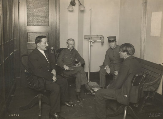A private interview between a young immigrant and an Ellis Island official. Two staff members [?] are also present