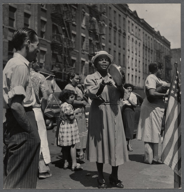 Crowded street scene with woman playing tambourine