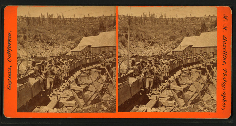Group portrait of men posed on cars of mine railroad.