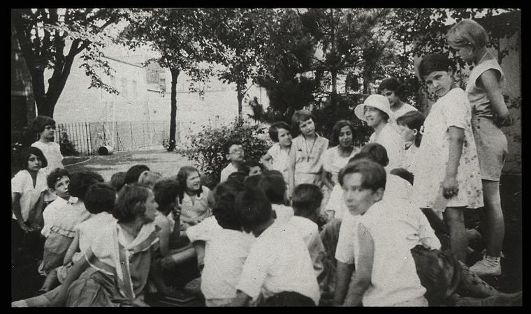 Work with schools : story hour in the open, librarian and children in park, ca. 1920s