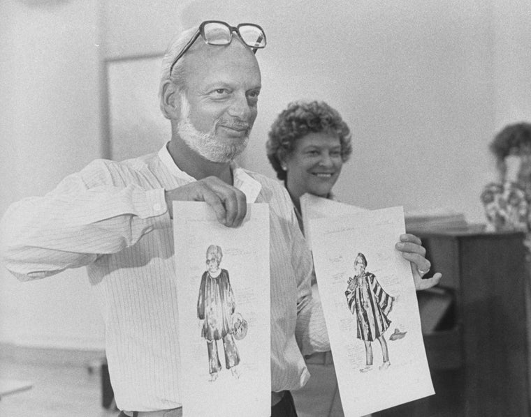 Director Harold Prince holding up renderings of costumes that would eventually be scrapped during a rehearsal of the Broadway production of the musical "Merrily We Roll Along".