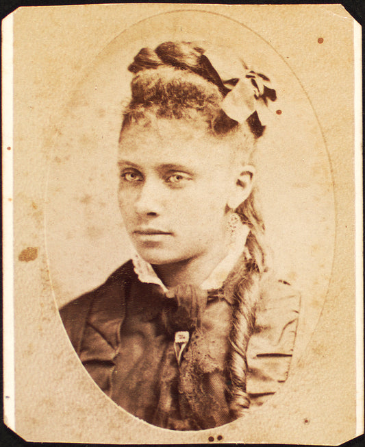 Oval portrait of unidentified young woman with long curl draped over chest. 'Redd' on verso.