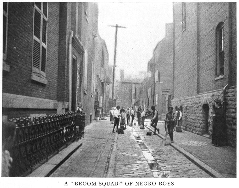 A "broom squad" of Negro boys; Which makes a regular business of sweeping several of the streets in the very worst slum district in Philadelphia; It gives them employment and it teaches them civic responsibility and pride; Miss Hancock at the right.