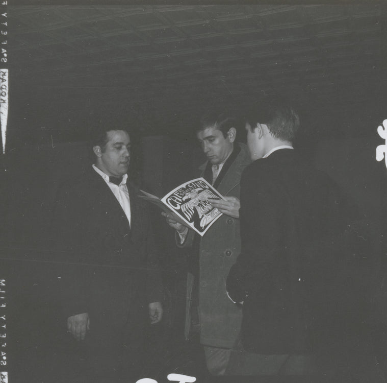 Edward Albee holding a program from the 1965 benefit to rebuild Caffe Cino after a fire, as Joe Cino (left) looks on