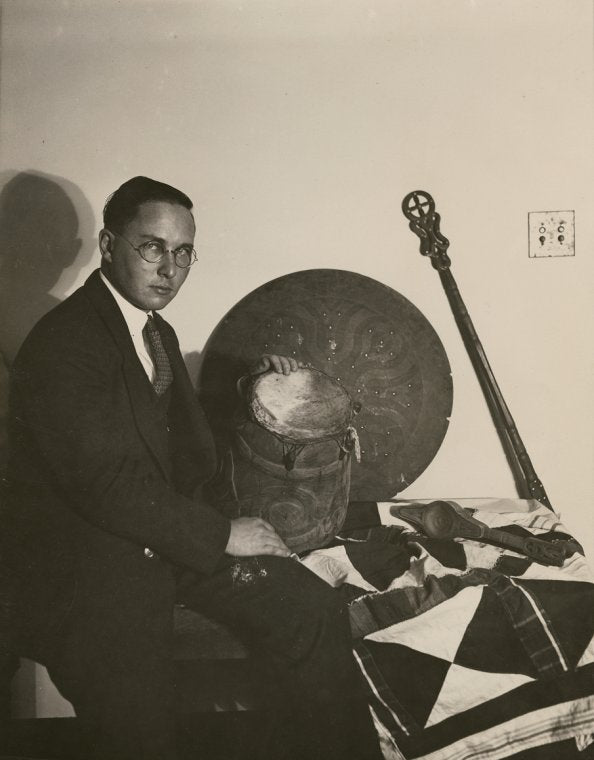Anthropologist Melville Herskovits with drum, surrounded by other Saramakan objects from Surinam